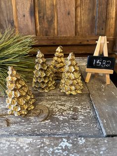 small gold pine cones sitting on top of a wooden table next to a chalkboard