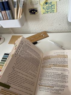 an open book sitting on top of a table next to some markers and pencils