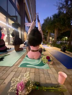 two women doing yoga outside at night with flowers on the floor and in front of them