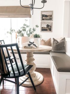 a dining room table with two chairs and a bench in front of it, next to a window