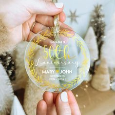 a person holding up a glass ornament with the words 50th anniversary printed on it