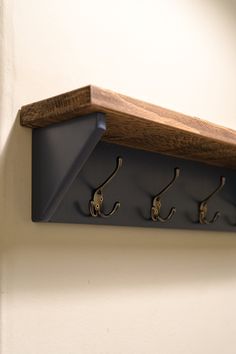 three hooks are attached to the wall and hang on it's side, with one hook in the middle