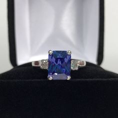 Beautiful Tanzanite* & White Sapphire Ring * 2.25ct Emerald Cut Violet Blue Tanzanite* measures 9mm x 7mm * 3.5mm Brilliant Cut White Sapphire Accents * 2.5cts Total weight * 14k White Gold * Size 9 Hallmarked & Gift Ready! Matching Earrings & Pendant Necklace is also Available! *Tanzanite is one of very few gemstones that cannot be grown in a Lab, however, these Laboratory Grown Simulate Stones are optically identical to a natural Tanzanite in color and are just as hard but, do not Trending Jewelry, White Sapphire Ring, Gifts For Fiance, Fine Art Jewelry, Tanzanite Ring, Tanzanite Gemstone, Blue Tanzanite, Three Stone Engagement Rings, Fine Jewelry Gift