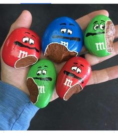 four rocks painted to look like m & m's are in the palm of someone's hand