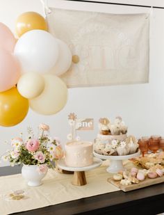 a table topped with lots of cake and balloons