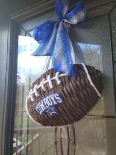 a football ornament hanging on the front door with a blue ribbon and bow