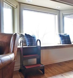 a brown leather chair sitting next to a window sill with pillows on it's sides