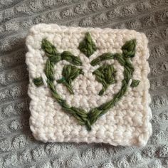 a crocheted square with leaves in the shape of a heart on top of it