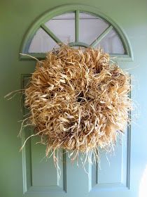 a wreath hanging on the front door of a green house with grass growing in it