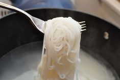 noodles being cooked in a pan with a fork