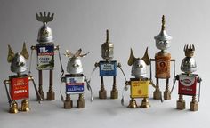 several metal robot figurines are lined up against a white background, one is gold and the other is silver