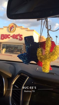 the inside of a car with some decorations hanging from it's dash board in front of a buc - eets store