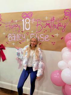 a woman standing in front of a happy 18th birthday sign