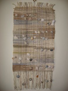 a woven wall hanging with shells on it