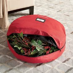 a red bag filled with greenery sitting on top of a floor next to a chair