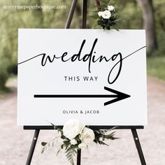 a sign that says, wedding this way with flowers on it and an arrow pointing to the right