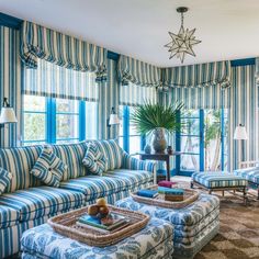 a living room filled with blue and white striped couches next to a window covered in curtains