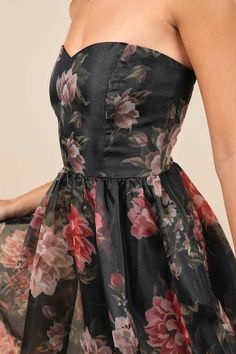 a woman wearing a black floral dress with red and pink flowers on the bottom half