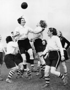 a group of young women playing soccer against each other on a field in black and white