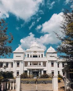 a large white building sitting under a cloudy blue sky