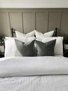 a bed with two pillows and some plants on the headboard in front of it