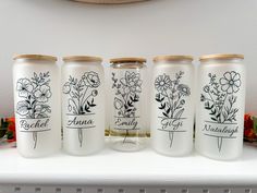 four jars with flowers on them sitting on a shelf