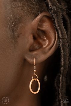 a close up of a woman's ear wearing gold earrings with an oval design