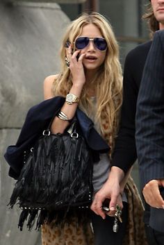 a woman talking on her cell phone while walking down the street with a man behind her