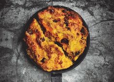 a skillet that has some food in it on top of a table next to a knife