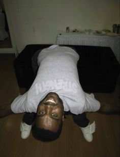 a man is upside down on the floor with his head up and hands behind his back