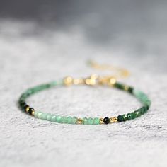 This handmade Emerald Bracelet for Women is dainty, but striking, and brings a colourful, exotic touch to any outfit. Stylish and minimal worn alone, but great to mix, match & stack. A very dainty, skinny bracelet with a delicate, feminine, minimal look - made with 2.75mm tiny sparkling Emeralds. Featuring genuine, natural, undyed Emeralds in shades of green ranging from deep forest green to emerald to jade and seafoam - all the beautiful greens of nature! Excellent cut with many facets to b Emerald Bracelet Gold, Green Emerald Bracelet, Delicate Feminine, Green Bracelet, Emerald Bracelet, Bracelet Love, Emerald Bead, Beads Bracelet Design, May Birthstone