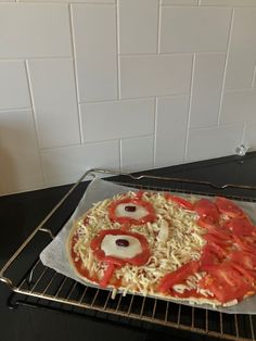 an uncooked pizza sitting on top of a metal rack in front of a white tiled wall