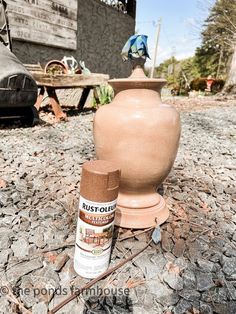 a brown vase sitting on top of a pile of rocks next to a paint roller