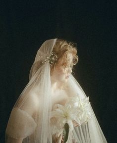 a woman wearing a veil and holding a flower