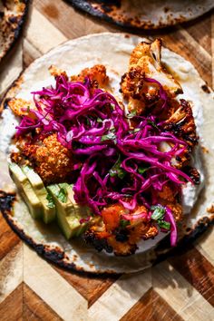 some food is sitting on a tortilla with red cabbage and avocado