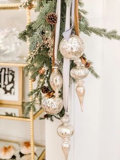 christmas decorations hanging from the side of a white door with pine cones and silver baubles