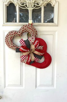 a heart shaped wreath hanging on the front door with ribbon attached to it's side