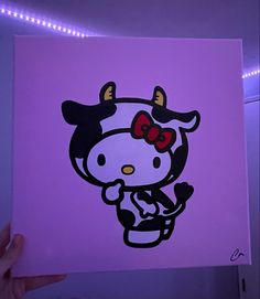 a person holding up a painting with a hello kitty on it