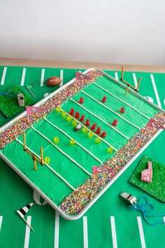 a cake shaped like a football field with sprinkles on it and other decorations