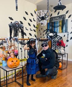 two people dressed up in halloween costumes posing for a photo with fake skeletons on the wall behind them