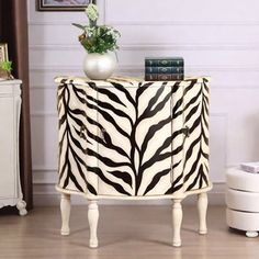 a white and black zebra print cabinet next to a vase on top of a table