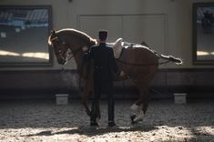 a man standing next to a brown horse