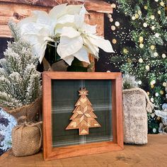 a wooden christmas tree in a frame on a table next to other holiday decorations and flowers