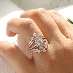 a woman's hand with a diamond ring on top of her finger and an engagement band in the middle