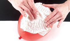 two hands on top of a red object with writing on it and one hand holding something