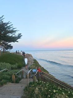 people are walking up and down the stairs to the beach at sunset or sunrise time