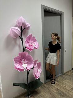 a woman standing next to a pink flower sculpture