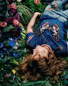 a woman laying on the ground surrounded by flowers