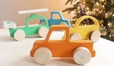 three wooden toy cars sitting in front of a christmas tree