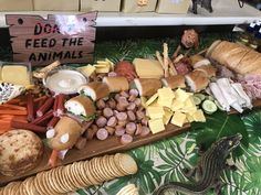 an assortment of cheeses, crackers and meats on a table with a sign that says do not feed the animals